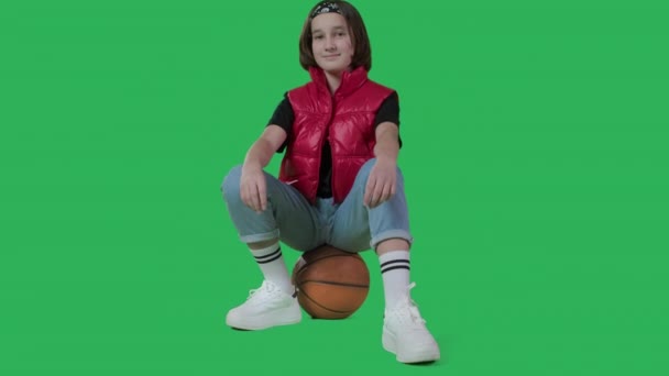Девочка-подросток сидит на баскетболе и щелкает пальцами — стоковое видео
