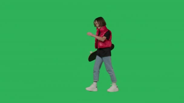 Adolescente menina segurando skate andando na tela verde — Vídeo de Stock