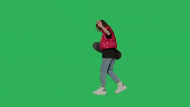 Genç kız elinde kaykayla yeşil ekranda yürüyor — Stok video