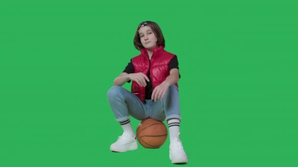 Teenage girl sits on basketball and snaps her fingers — Stockvideo