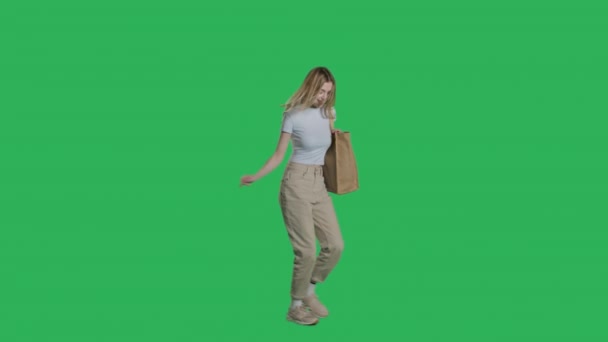 Jonge vrouw in casual kleding wandelingen met boodschappentas — Stockvideo