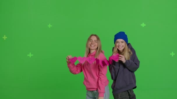 Girls hug and stretch a ribbon of pink hearts — Stock Video