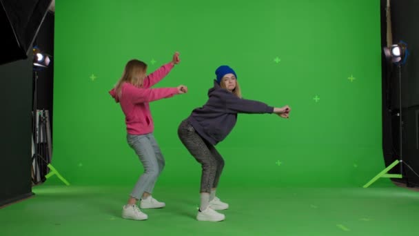 Two girls dancing over green screen background — Stok video