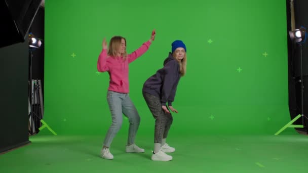 Two girls dancing over green screen background — Stok video