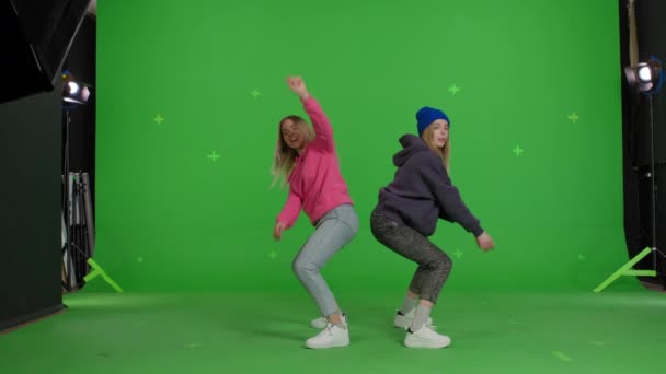 Two girls dancing over green screen background — Stock video