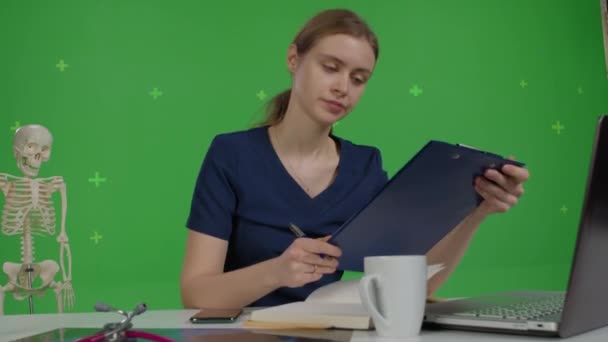 Blanke vrouwelijke arts zit aan haar bureau — Stockvideo