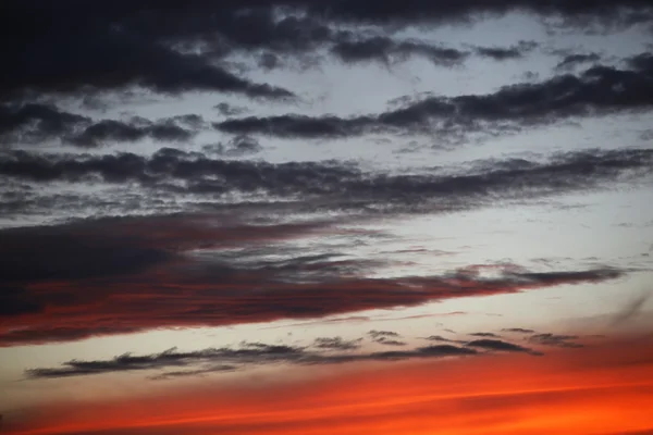 Красный закат над морем, густые темные и светлые облака — стоковое фото