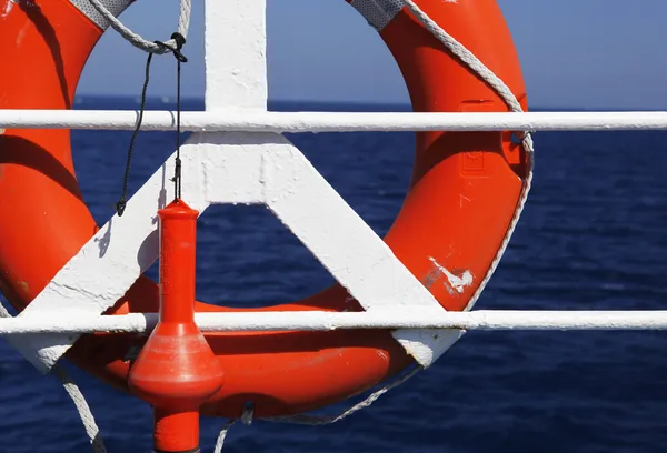 Boa di vita rossa di fronte al mare blu e alla nave bianca — Foto Stock