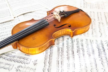 Old violin lying on the sheet of music clipart