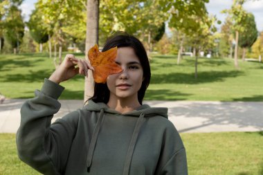 Güzel esmer kız sonbaharda parkta yürüyor.