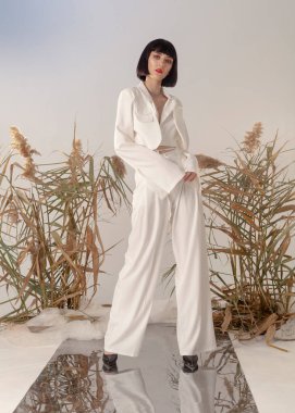 fashionable brunette in a light suit posing for a catalog