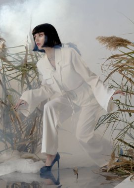 fashionable brunette in a light suit posing for a catalog