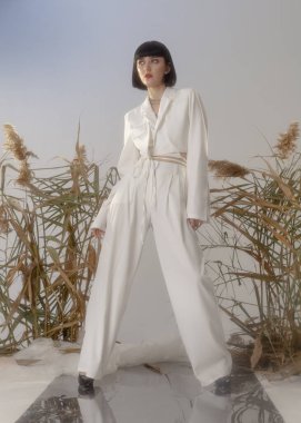 fashionable brunette in a light suit posing for a catalog