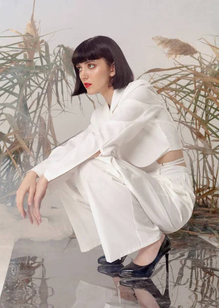 fashionable brunette in a light suit posing for a catalog
