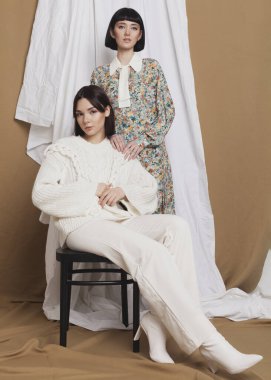 cute portrait of two brunettes in spring clothes on a background of fabrics