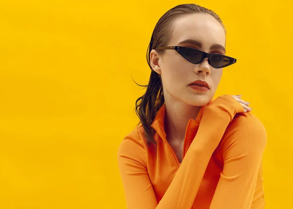 Sarı arka planda gözlüklü bir kızın şık portresi.