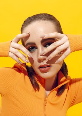 Sarı arka planda parlak makyajlı bir kızın güzel portresi.