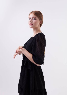 Beyaz arka planda siyah elbiseli güzel sarışın bir kadının portresi.