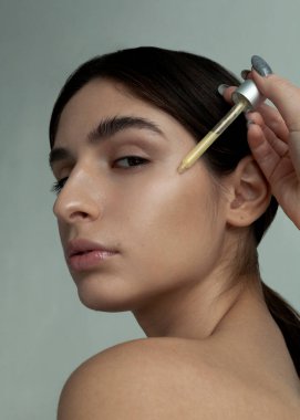 Güzel esmer yüz serumu uyguluyor.