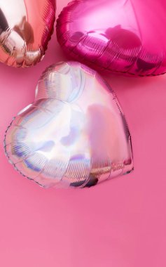 Pembe arka planda kalp şeklinde balonlar.