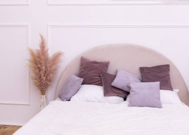 Yatak odasında çok renkli yastıklar olan yatak başlığı.