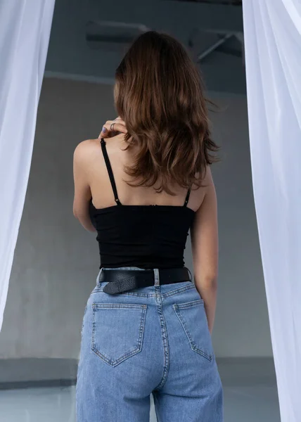 Güzel, koyu saçlı bir kız arkasında duruyor.