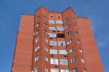 Çok katlı tuğla dış görünüş. Mavi gökyüzüne karşı kırmızı..