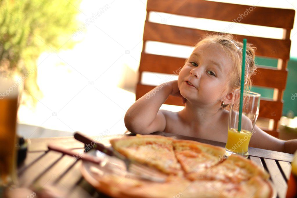 Happy little girl eating pizza