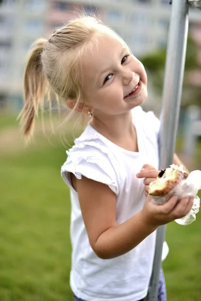 Vrij klein meisje eten een broodje geïsoleerd op witte achtergrond — Stockfoto