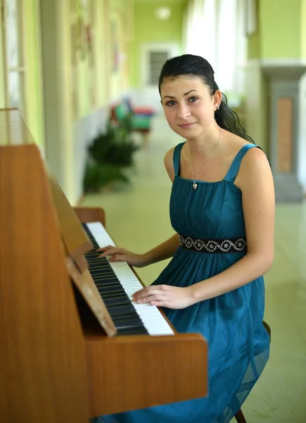 Mooie jonge aantrekkelijke vrouw in cocktail jurk en piano — Stockfoto