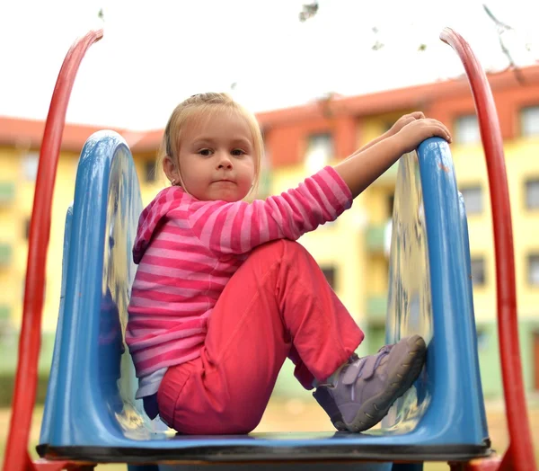 Attraktives kleines Mädchen auf Spielgeräten im Freien — Stockfoto