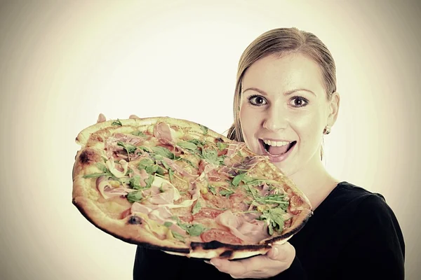Porträt einer jungen Frau, die vor weißem Hintergrund eine Pizza isst — Stockfoto