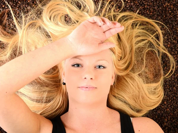 Portrait of a girl's face drowned in coffee beans — Stock Photo, Image