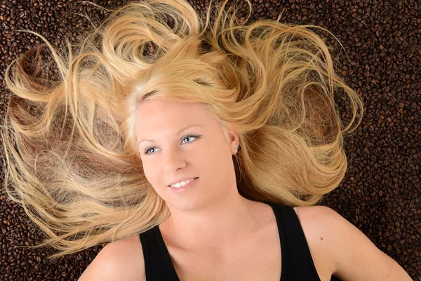 Portrait of a girl's face drowned in coffee beans — Stock Photo, Image