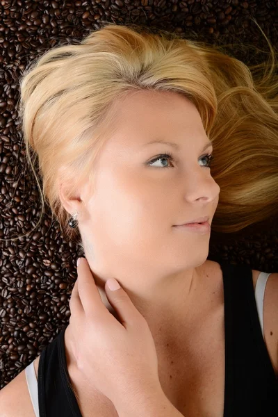 Portrait of a girl's face drowned in coffee beans — Stock Photo, Image