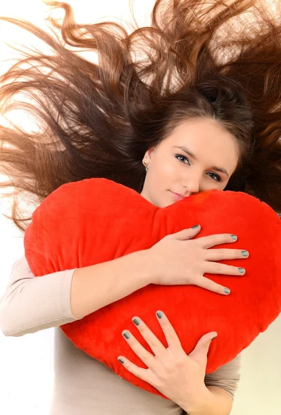 Mooie vrouw met rood hart-vormige kussen — Stockfoto