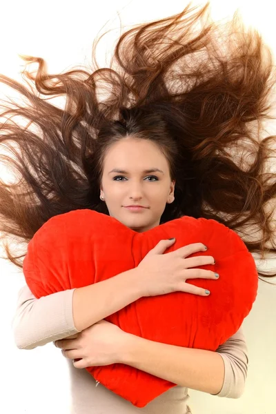 Όμορφη γυναίκα με το κόκκινο σχήμα καρδιάς μαξιλάρι — Φωτογραφία Αρχείου
