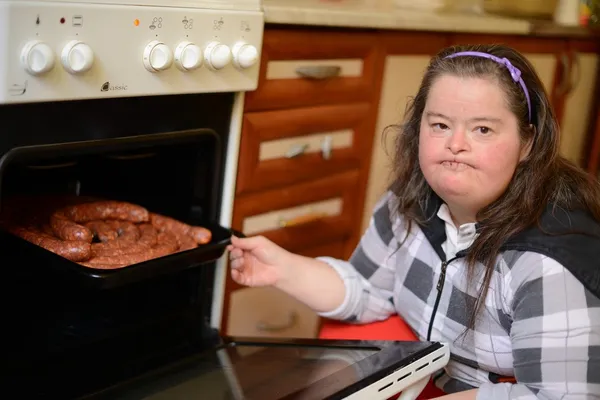 Aantrekkelijke down syndroom vrouw aanspanning in de keuken — Stockfoto