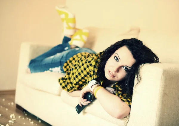 Felice giovane donna guardando la tv sul divano — Foto Stock