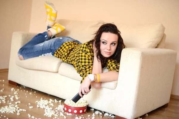 Feliz joven mujer viendo la televisión en el sofá —  Fotos de Stock