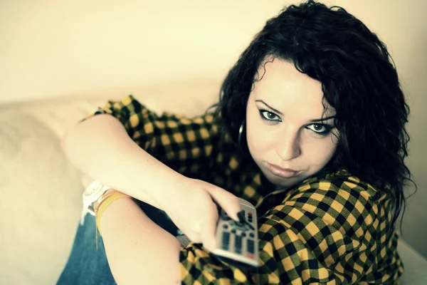 Happy young woman watching tv on sofa — Stock Photo, Image