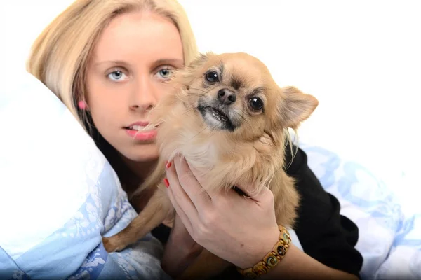 Uma jovem feliz deitada em sua cama com seu filhote de cachorro . — Fotografia de Stock