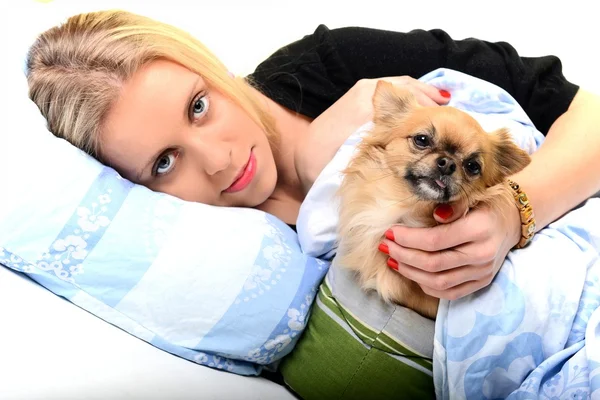 Eine glückliche junge Frau liegt mit ihrem Welpen auf ihrem Bett. — Stockfoto