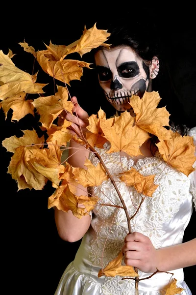 Girl with painting dead mask skull with leaves — Stock Photo, Image