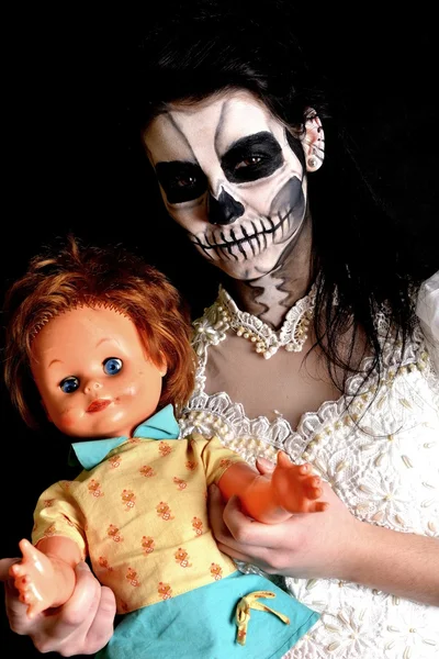 Girl with painting dead mask skull with doll — Stock Photo, Image