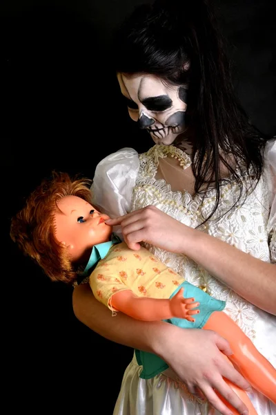 Girl with painting dead mask skull with doll — Stock Photo, Image