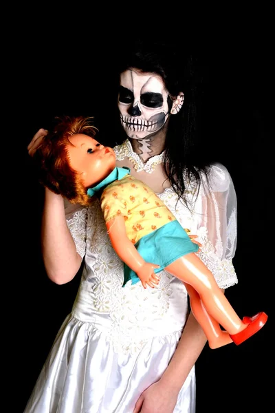 Girl with painting dead mask skull with doll — Stock Photo, Image