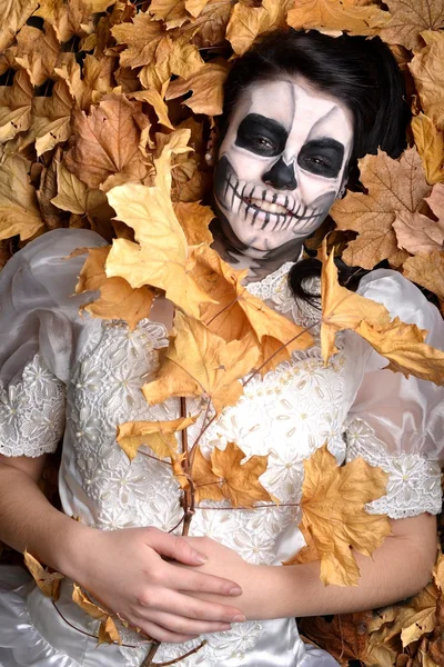 Girl with painting dead mask skull with leaves — Stock Photo, Image