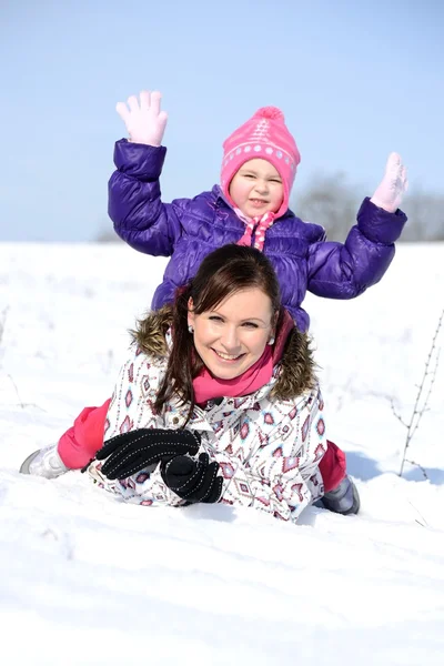 Madre si siede sulla slitta in parco con bambino in inverno — Foto Stock