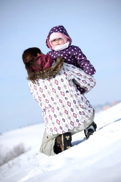 Мать сидит на санях в парке с ребенком зимой — стоковое фото